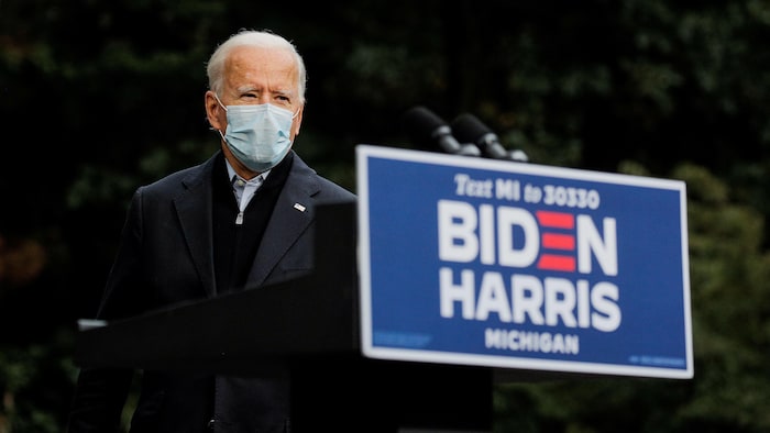 Joe Biden porte un masque et s'approche d'un lutrin.