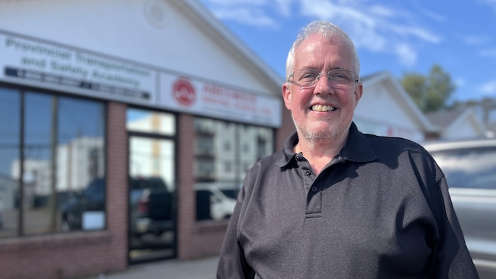 Joe Byrne pose pour la photo devant la façade de l'école de conduite Abgweit.