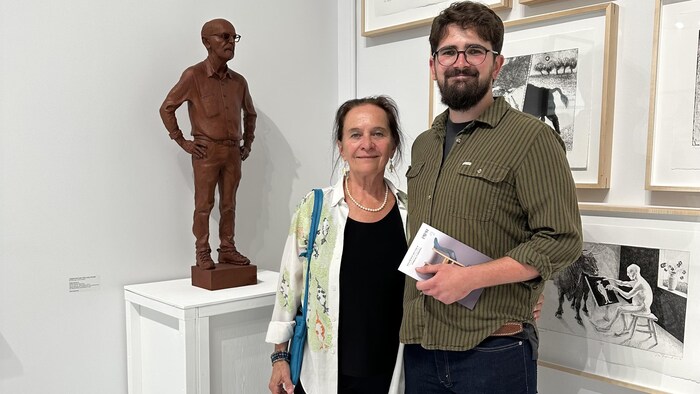Une femme et un homme posent devant une statue dans une galerie d'art.