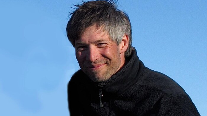 Une homme regarde la caméra en souriant.
