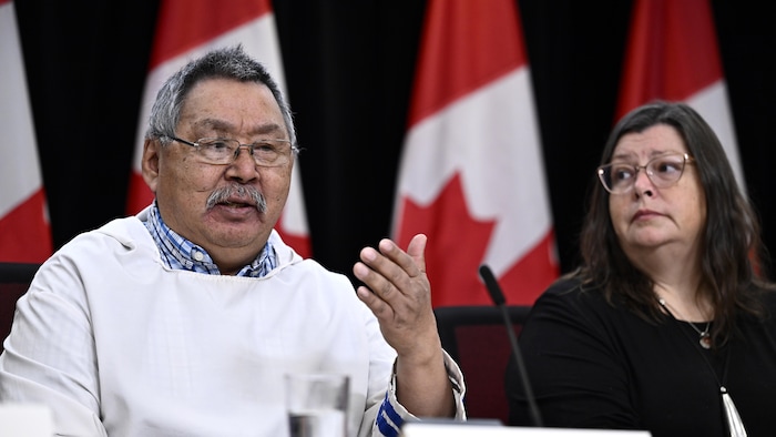 Un homme et une femme sont assis devant des drapeaux du Canada et répondent à des questions durant une conférence de presse, à Ottawa, le 27&nbsp;novembre&nbsp;2023.