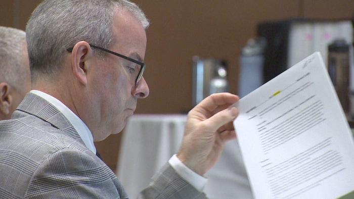 Un avocat assis consulte des documents d'un air sérieux.