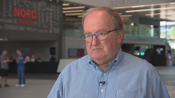 Un homme qui porte des lunettes dans l'atrium de Radio-Canada à Montréal.