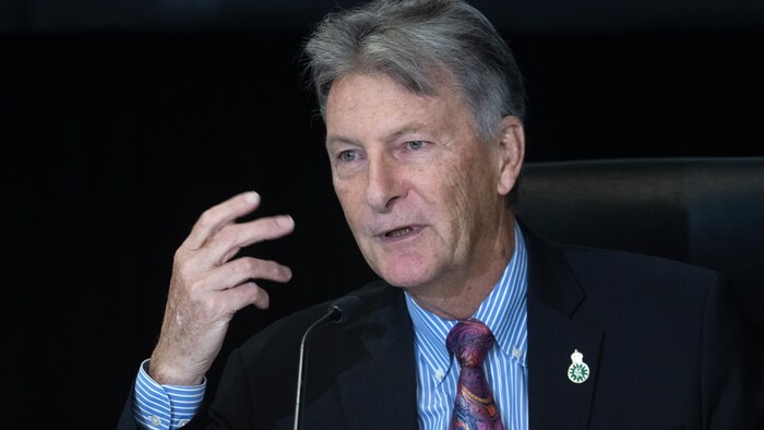 John McKay speaks into a microphone.