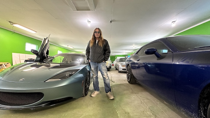 John Mysyk est dans un garage dans lequel des voitures de sport sont garées.