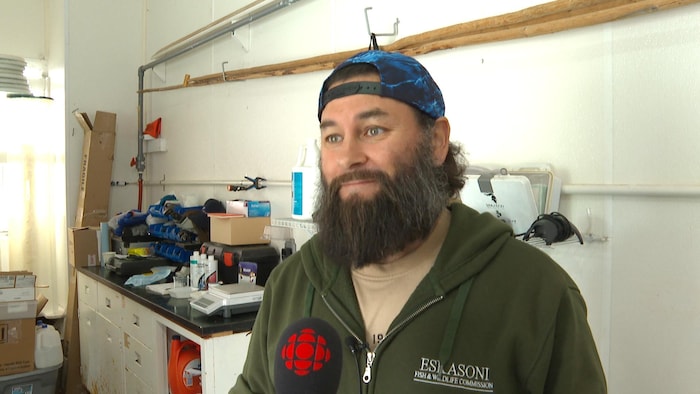Un homme avec une longue barbe dans un atelier.