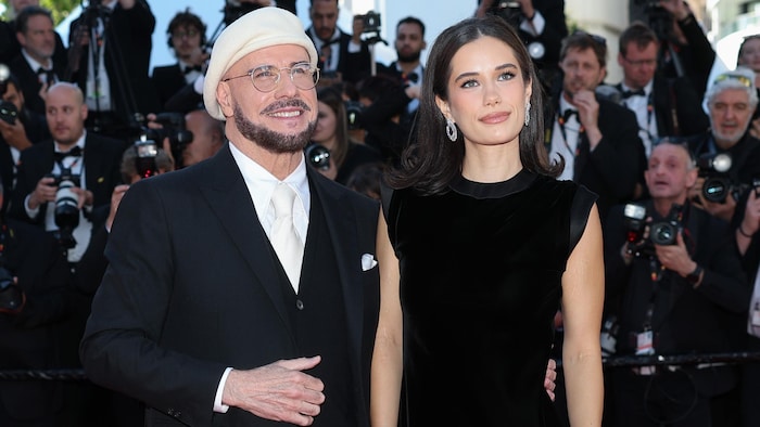 Un homme portant un béret beige et une femme portant une robe noire sourient.