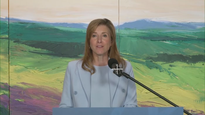La ministre albertaine Tanya Fir est debout devant un pupitre et s'adresse à un auditoire. 