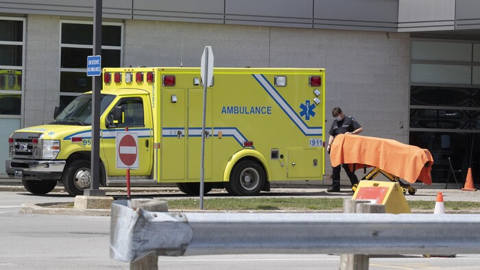Un ambulancier transporte une civière vers une ambulance.