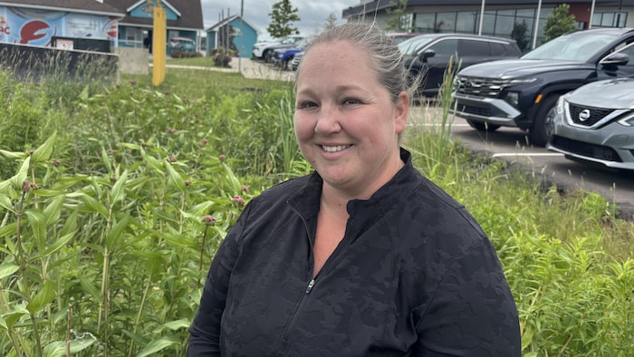 Une personne souriante devant des plantes vertes dans un canal de ruissellement.
