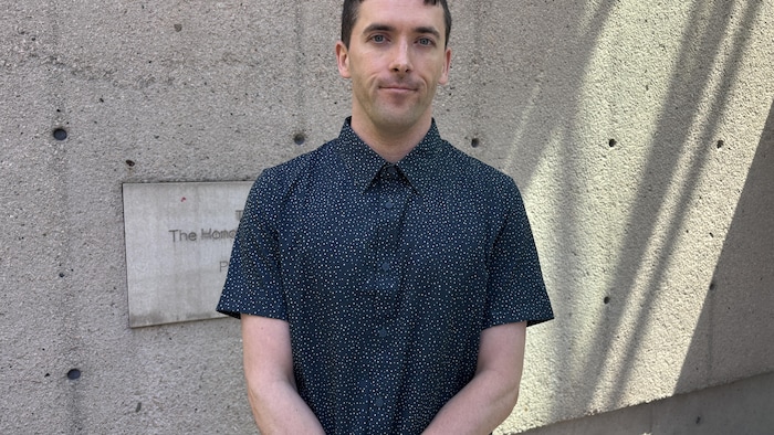 Jon Girard est debout devant un mur en béton.