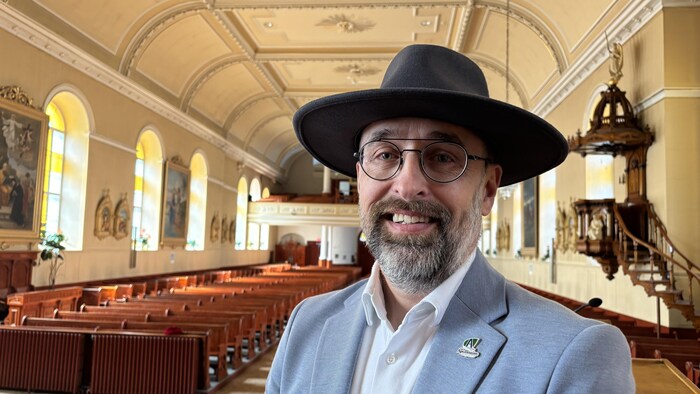 Un homme souriant devant la nef à l'intérieur d'une église.