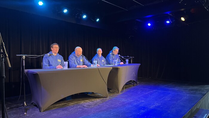 Quatre hommes sont assis devant un micro pour prendre la parole lors d'une conférence de presse tenue à Jonquière.