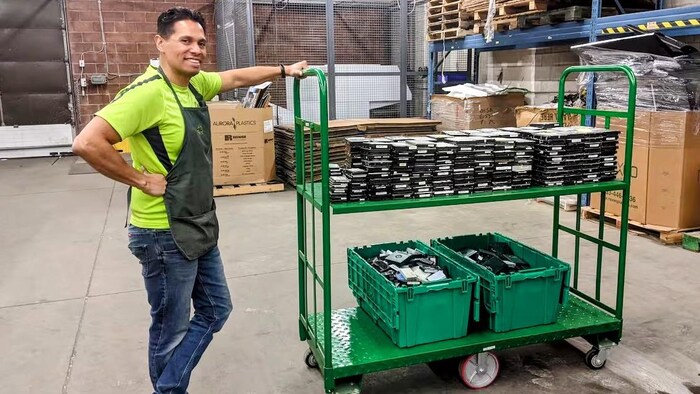 José Palacios avec un chariot rempli de boîtes contenant des déchets électroniques.