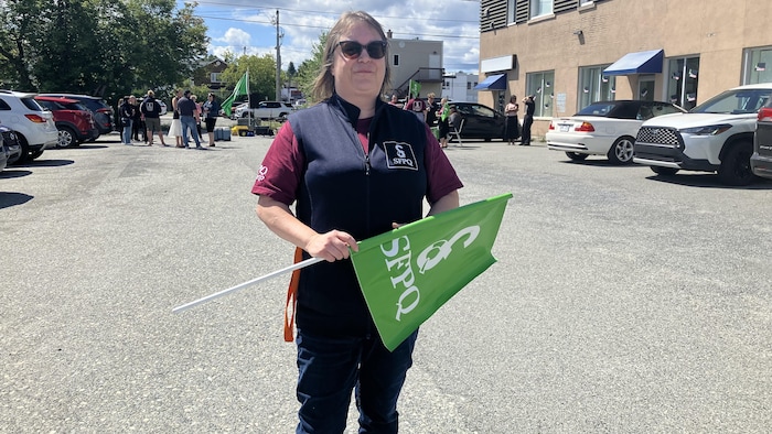 Josée Jolette, drapeau du SFPQ en main, pose pour la caméra sans vraiment sourire.