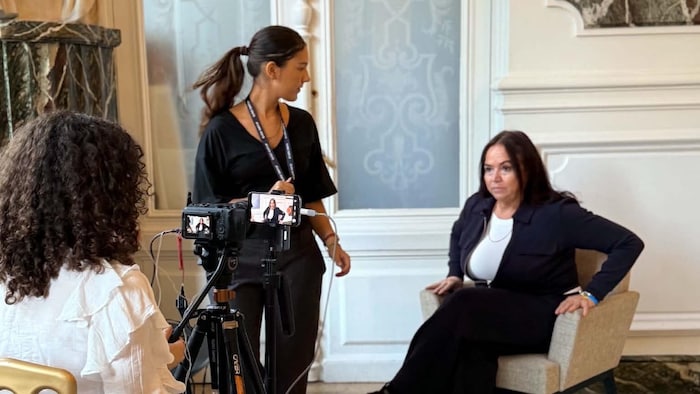 Une femme assise sur un fauteuil et posant pour un photographe.