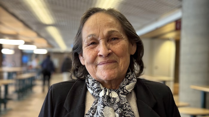 Une personne souriante à l'intérieur d'un édifice.