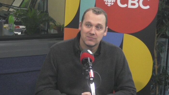 Un homme est assis devant un micro dans un studio de radio de CBC, à Edmonton, le 9 avril 2024.