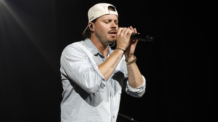 Un homme portant une casquette chante dans un micro. 