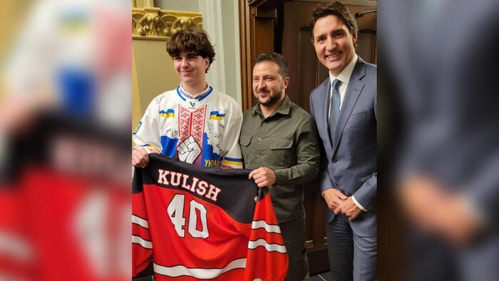 Matvii Kulish, Volodymyr Zelensky et Justin Trudeau prennent la pose avec un chandail de hockey offert au président ukrainien.