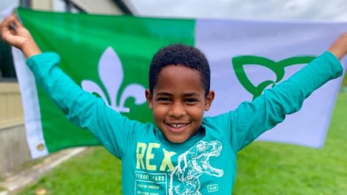 تلميذ في مدرسة ابتدائية في كورنوال في أونتاريو يحمل راية الناطقين بالفرنسية في هذه المقاطعة وهي باللونيْن الأبيض والأخضر.