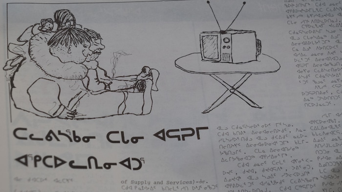 Archives du journal Atuarnik, écrit en anglais et en alphabet syllabique, avec une illustration de deux personnes qui regarde la télé.