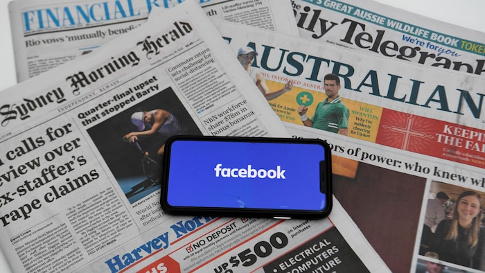 Des journaux avec un téléphone sur lequel on voit le logo de Facebook.