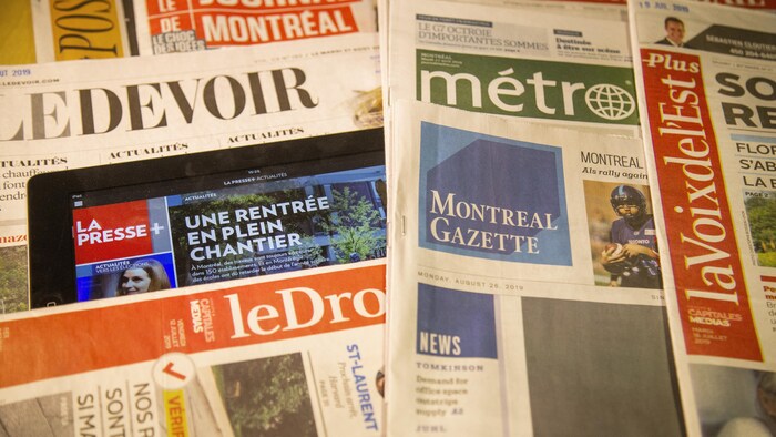 Des copies du Devoir, du Journal de Montréal, du journal Métro, de la Voix de l'Est, du Droit et un iPad montrant la Presse +