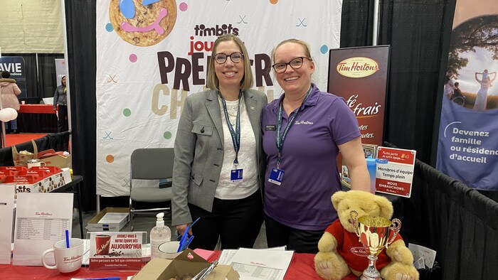 Deux femmes montrent leur kiosque de recrutement pour l'entreprise Tim Hortons. 