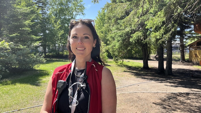 Une femme pose devant des arbres. 