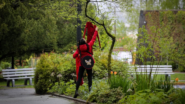 Une personne accroche une robe rouge dans un arbre. 
