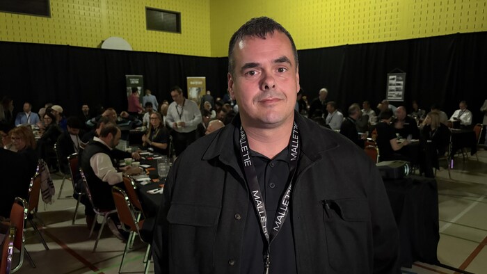 Un homme pose dans une salle de conférence.
