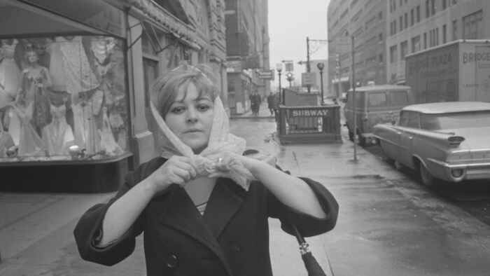 Une femme attache son foulard dans une rue de New York dans les années 1960.