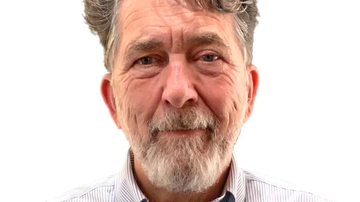 Un homme en chemise fixe l'appareil-photo.