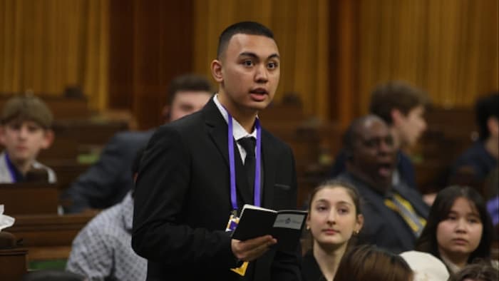 Un jeune homme prend la parole dans une assemblée.
