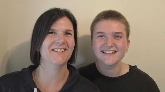 Une femme et un adolescent sourient à la caméra