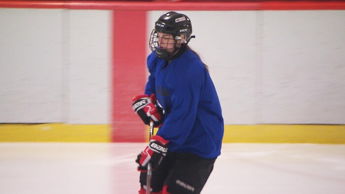 Julie Cormier en tenue de hockey sur la glace avec un bâton dans les mains.