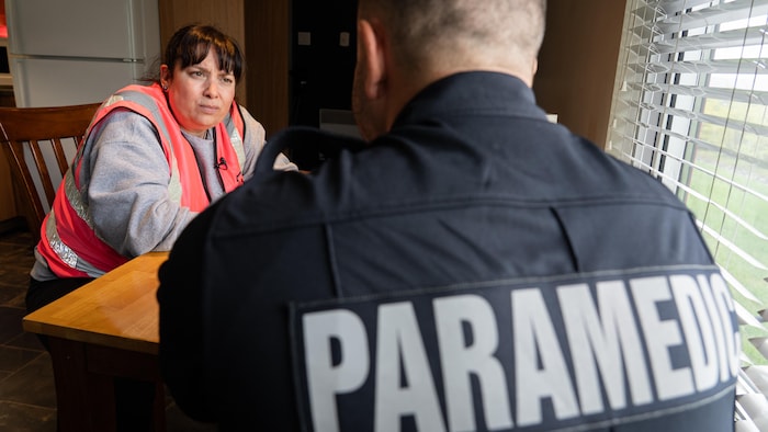 Une femme regarde un ambulancier lors d'une discussion à une table.