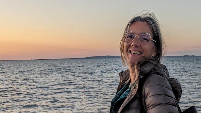 Julie Ried Forget devant le fleuve au coucher du soleil.