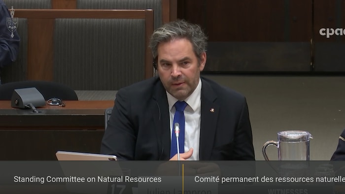 Julien Lampron témoigne devant un comité dans une salle.