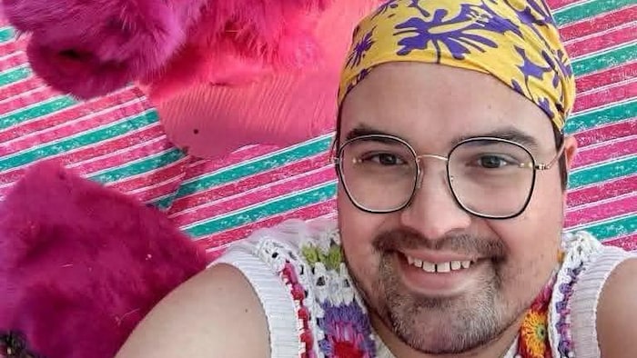 Un homme prend un égoportrait souriant, une vache rose derrière lui.