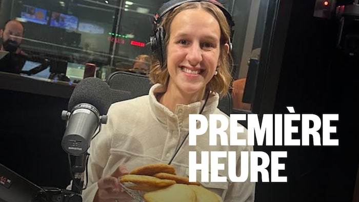 Une femme qui sourit dans un studio radio avec un pot de biscuits à la main.