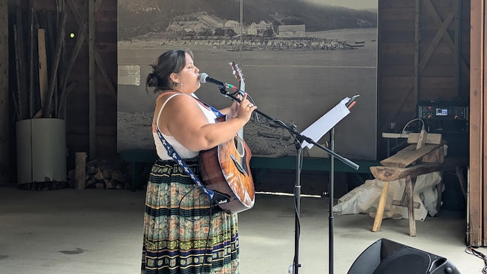 The singer wears a guitar and sings on the microphone.