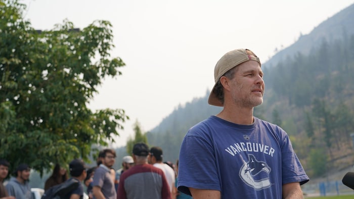 Un homme debout devant une foule et une montagne en arrière-plan.