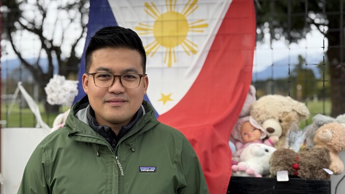 Un homme regarde l'objectif; un drapeau philippin est en arrière-plan.