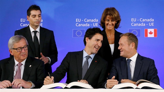 من اليمين، جلوساً: رئيس المجلس الأوروبي دونالد تاسك ورئيس الحكومة الكندية جوستان ترودو ورئيس المفوضية الأوروبية جان كلود يونكر خلال مراسم التوقيع على الاتفاق الاقتصادي والتجاري الشامل بين كندا والاتحاد الأوروبي في 30 تشرين الأول (أكتوبر) 2016 في بروكسل.