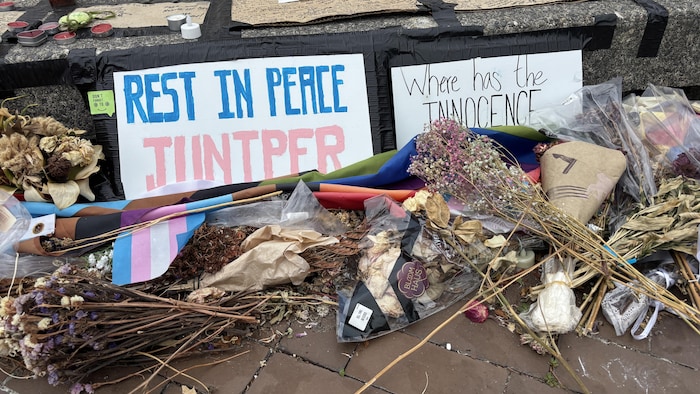 Des gerbes de fleurs et des messages au pied d'un monument. 