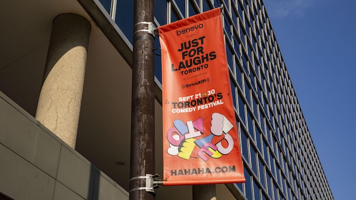 Une bannière du festival Just for Laughs 2023 à l'intersection des rues Yonge et Front, à Toronto.