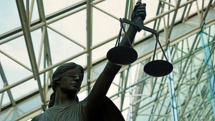 Une statue tient haut dans sa main une balance, le symbole de la justice