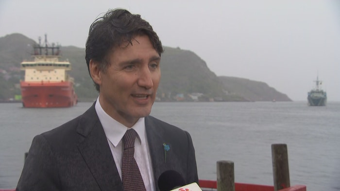 Justin Trudeau in front of the ocean, in a cave. 